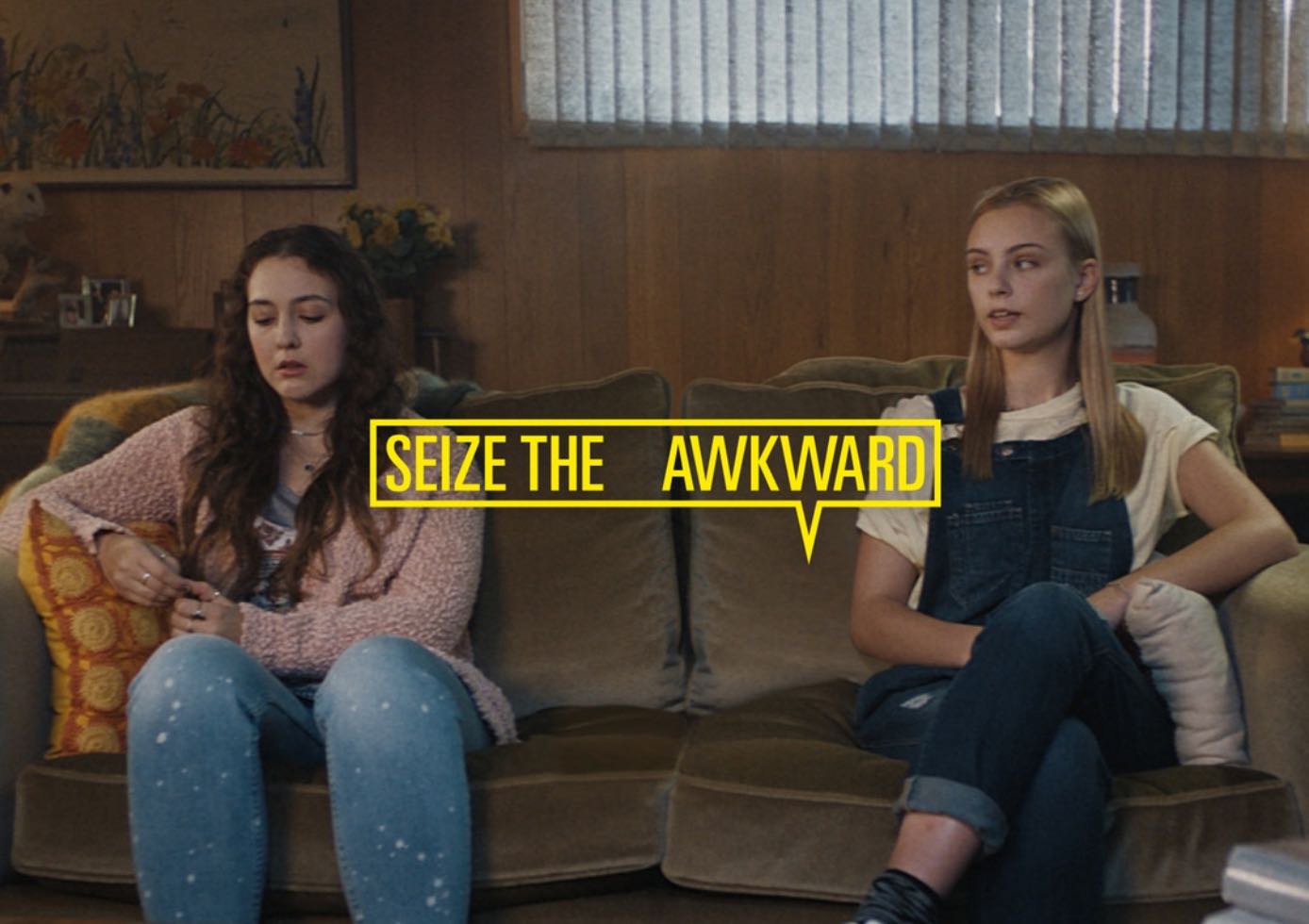 Two young women on couch for Seize the Awkward