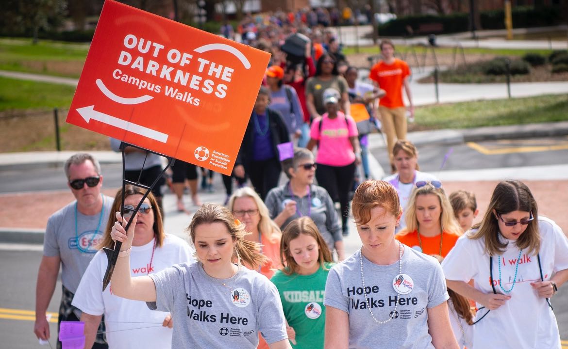 Crowd walking with Out of the Darkness sign